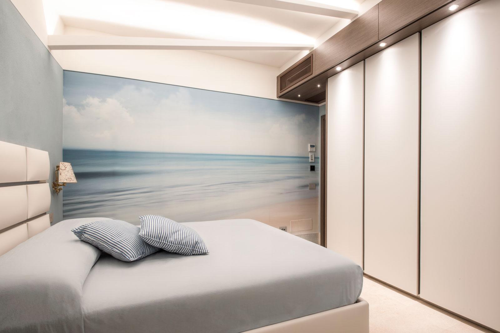 Camera da letto, armadio con sportelli in ecopelle bianca e illuminazione integrata, carta da parati a tema marino