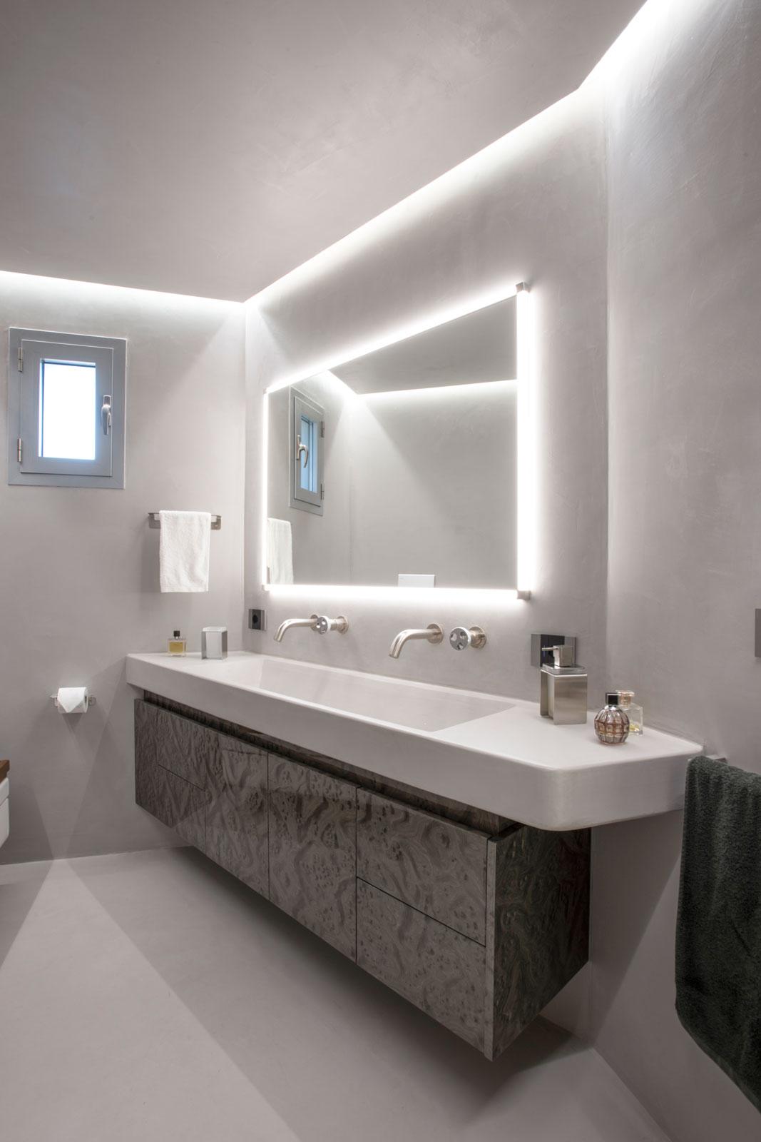 Bagno moderno in resina di cemento, illuminazione perimetrale, lavabo doppio in resina e mobile sospeso in radica grigio