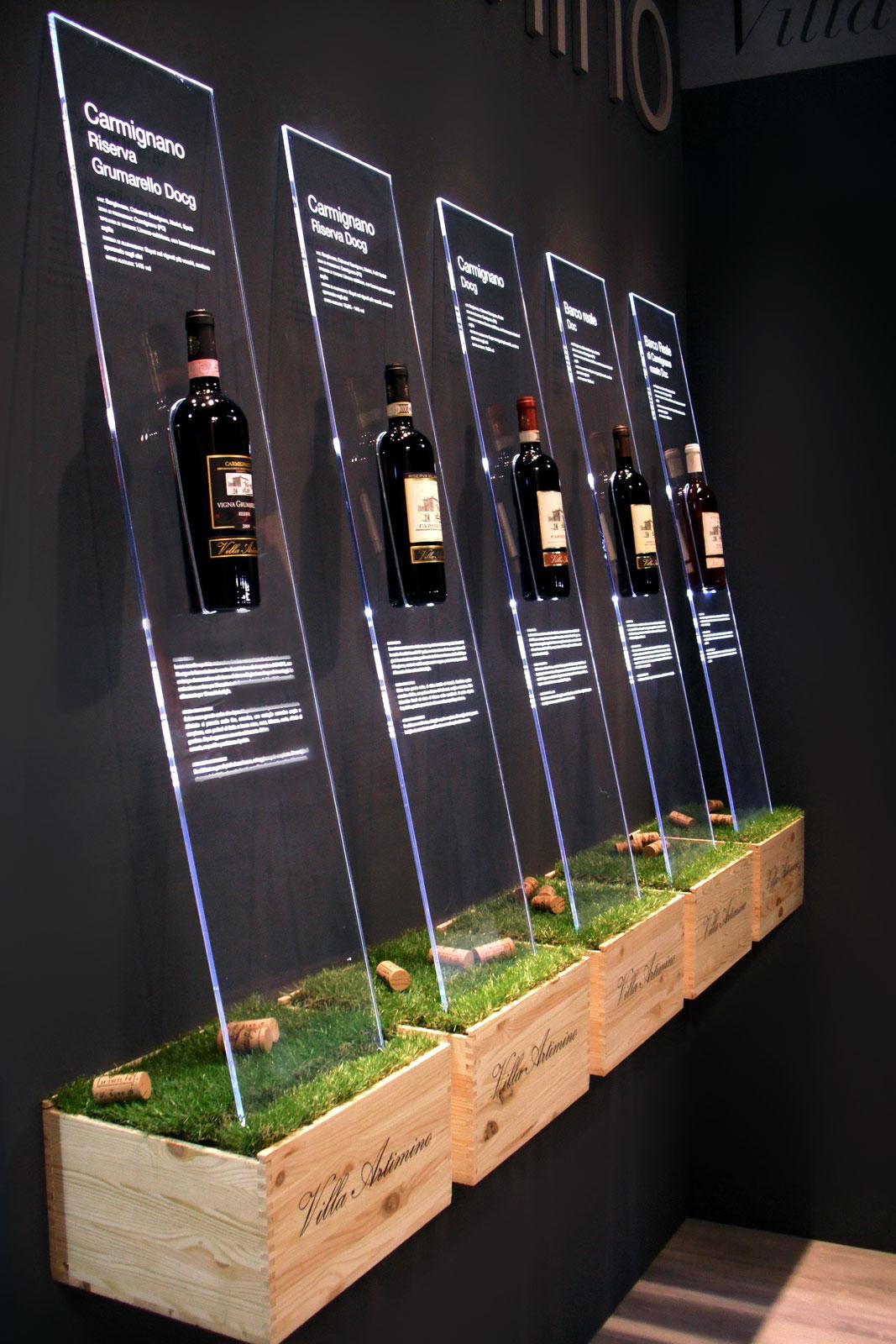 Parete espositiva di vini realizzata con cassette in legno, lastre in plexiglassi con illuminazione a led