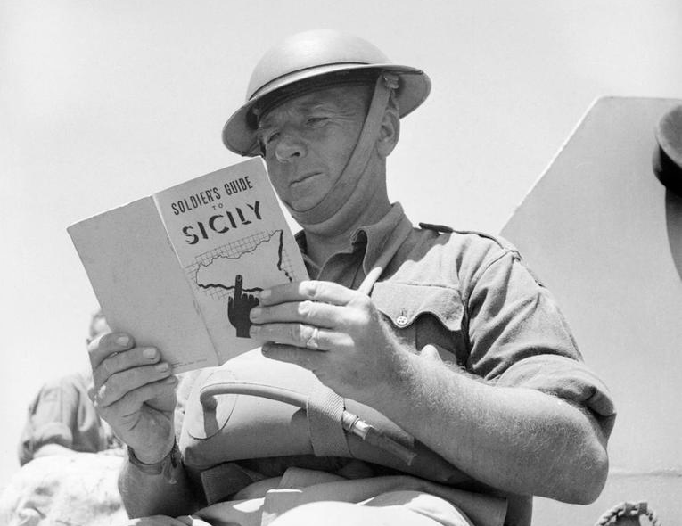 Un soldato britannico si documenta sulla Sicilia, obiettivo della prossima invasione alleata lug.'43