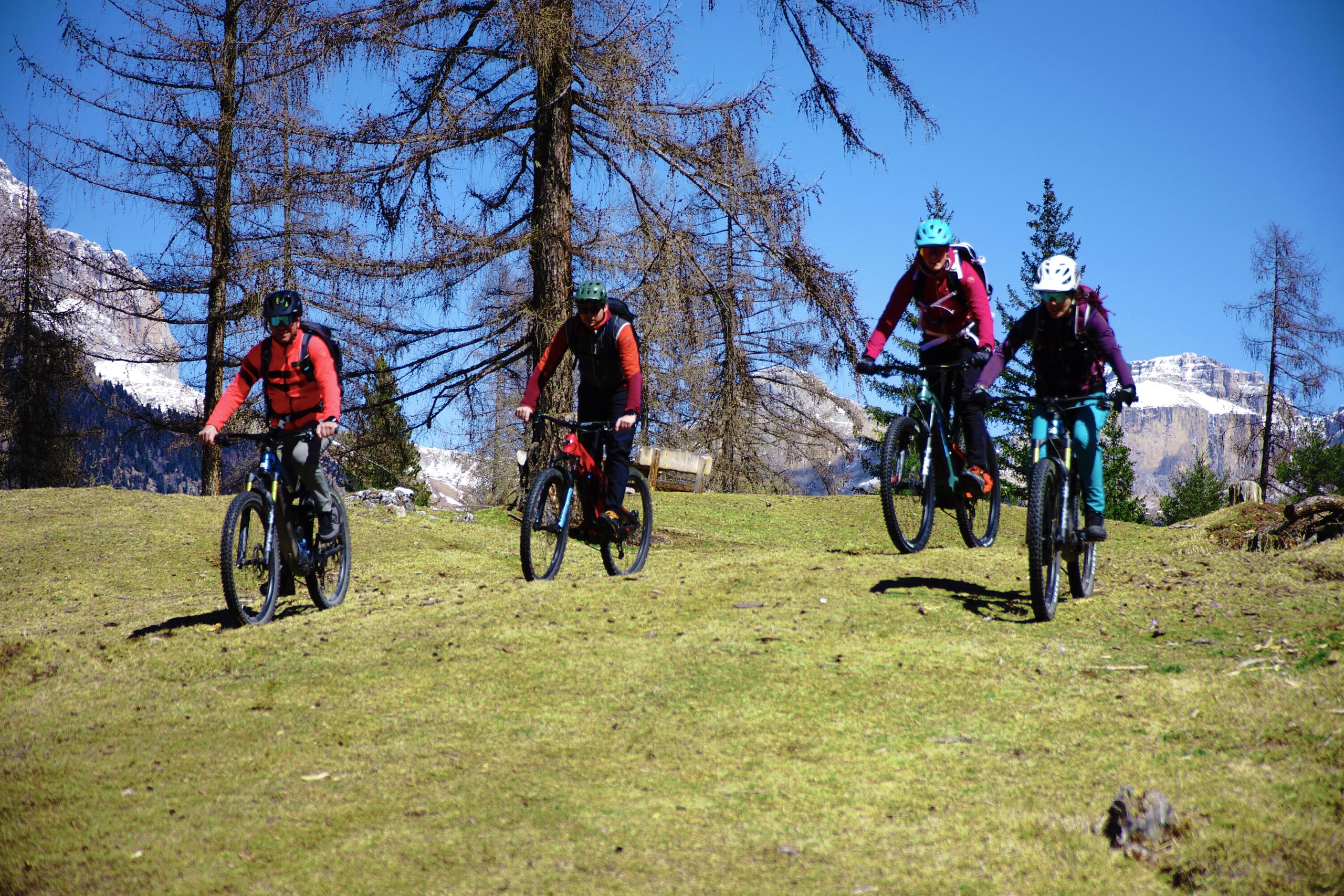 4 mountainbiker die auf einem Hügel im Fassatal fahrradfahren