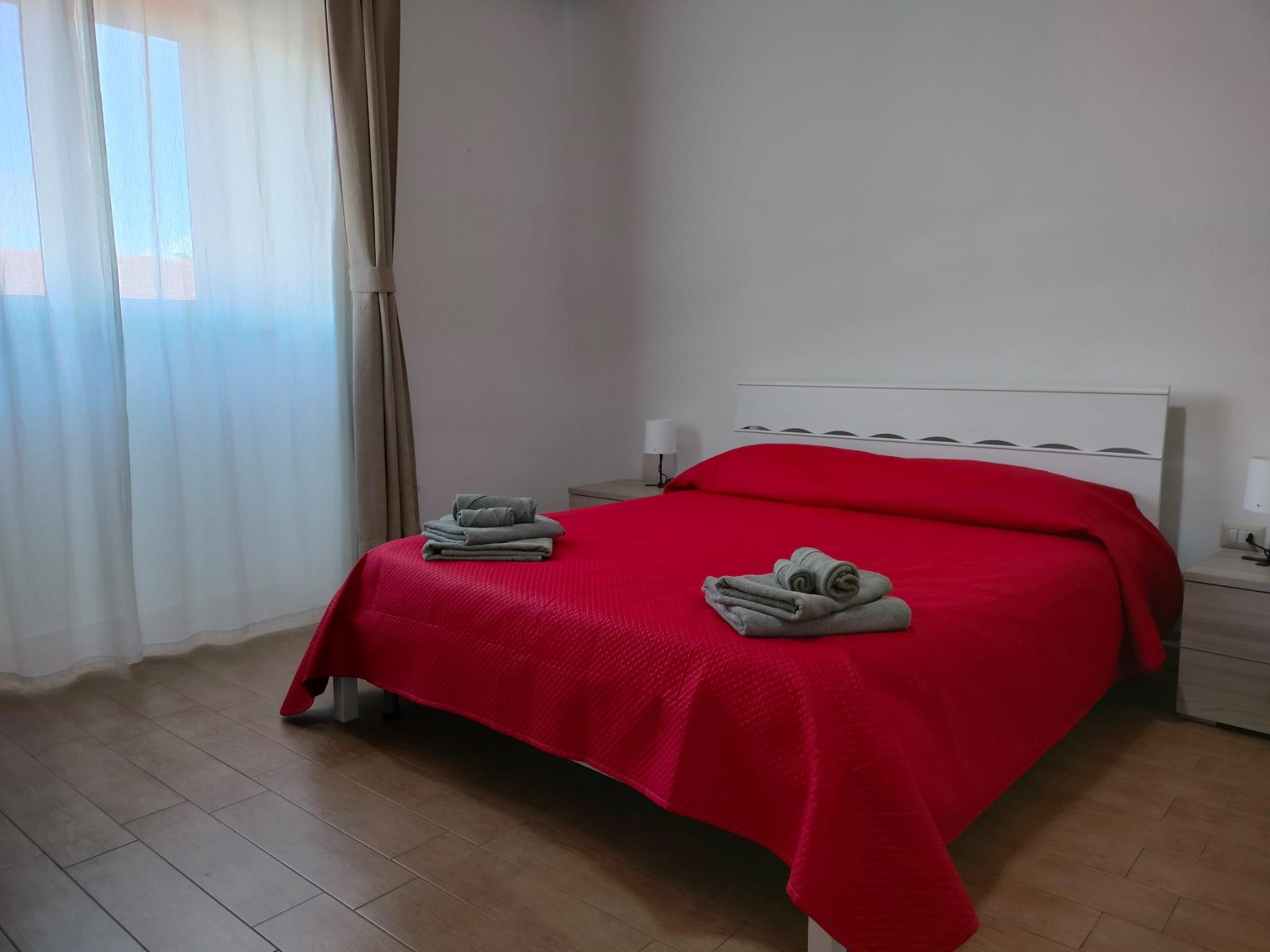 Camera matrimoniale dai colori caldi, prevale il rosso, asciugamani, tende e soffitto con travi in legno a vista, comodità e privacy in un intero appartamento dotato di ogni comfort: bagno e cucina ad uso esclusivo.